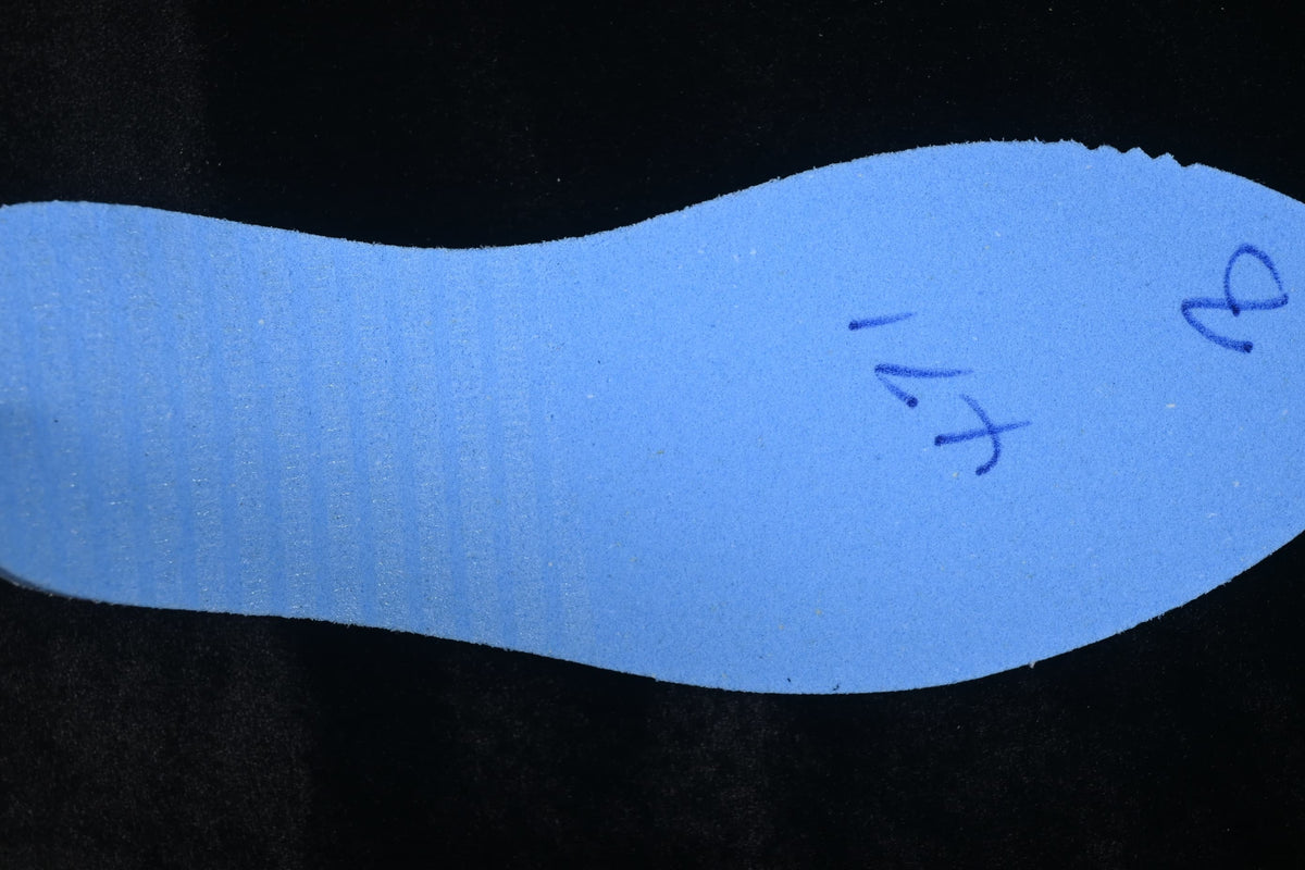 Reverse side of a shoe insole with handwritten markings.