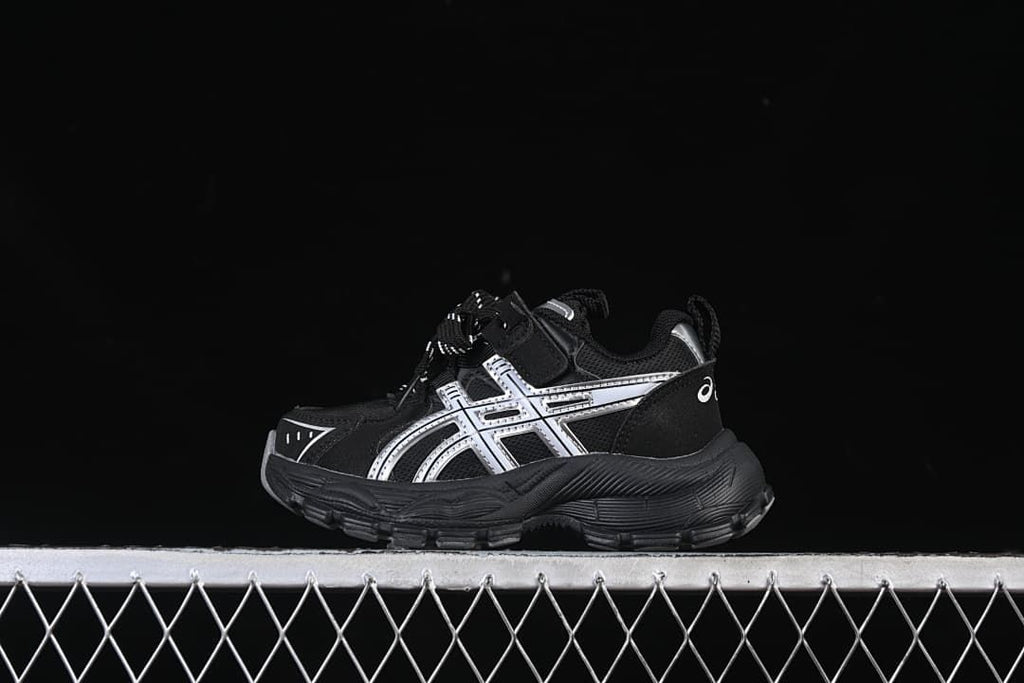 Black sneaker with silver side details shown in profile.