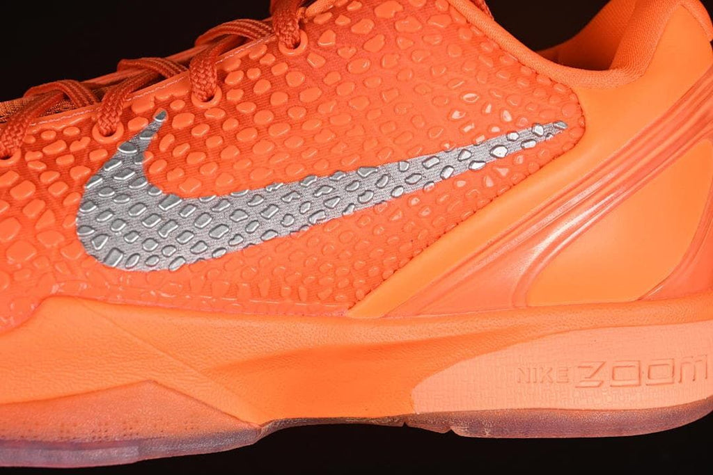 Close-up of textured orange upper, silver Swoosh, and midsole