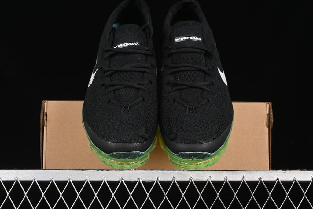 Front view of the pair showing black knit uppers and green-tinted toe sections of the soles.