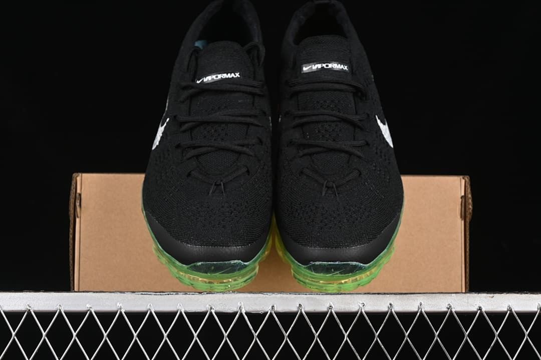 Front view of the pair showing black knit uppers and green-tinted toe sections of the soles.