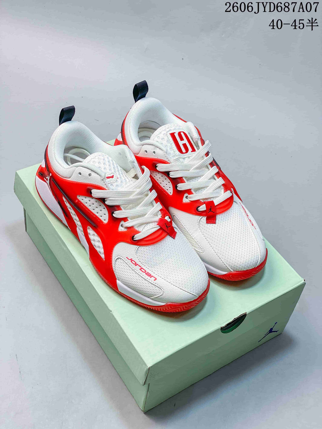 Pair of white and bright red Jordan Heir PF basketball shoes on a shoebox