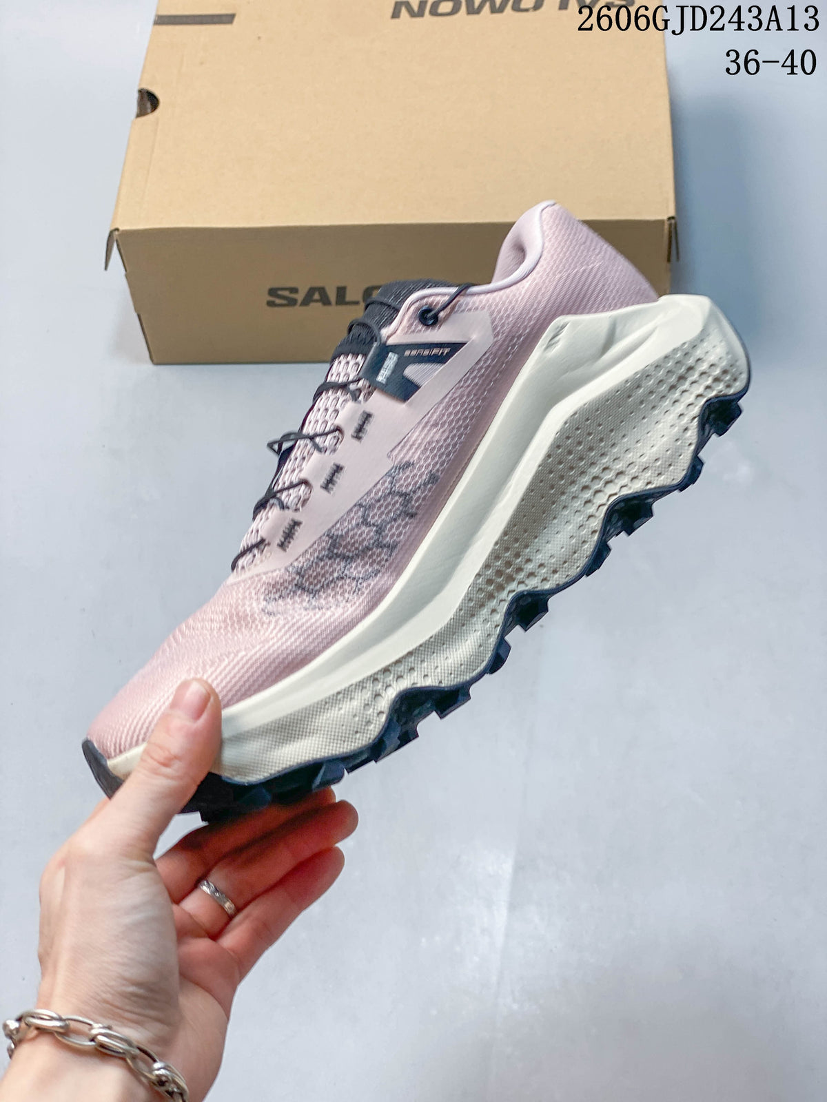 Side view of the pink Salomon trail running shoe, showing its midsole and lugged outsole.