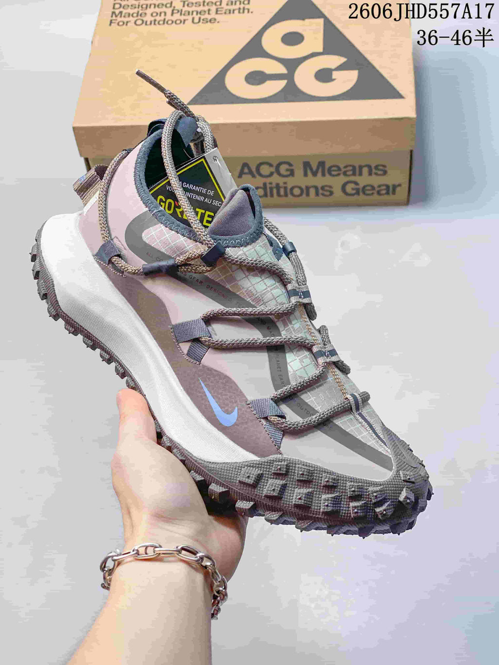 Nike ACG Mountain Fly sneaker in pale pink, gray, and blue with cord laces.