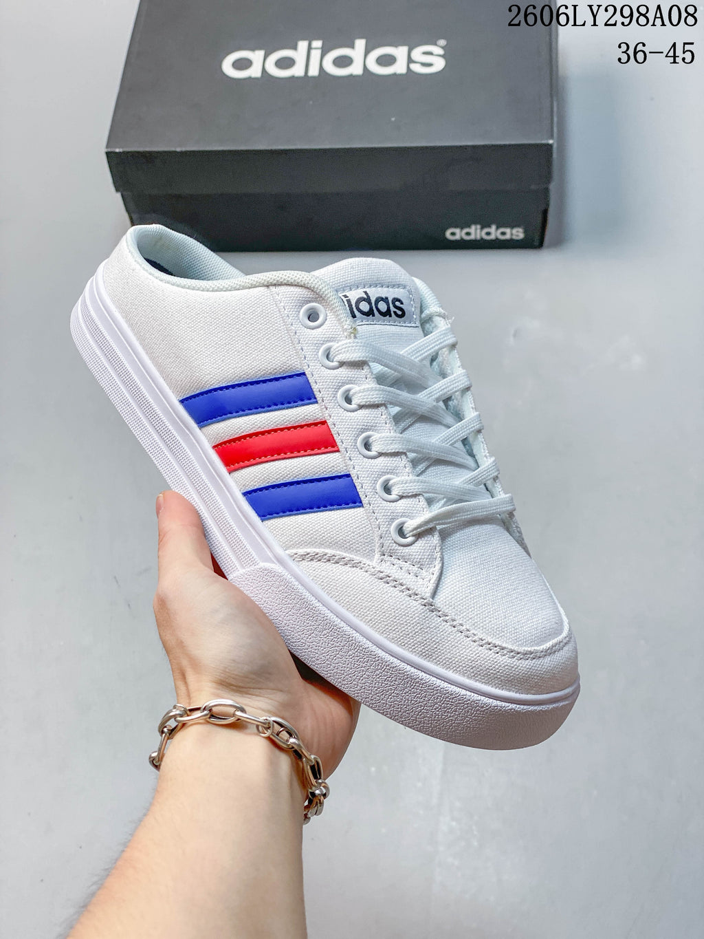 Close-up of a white adidas mule sneaker with blue and red side stripes.