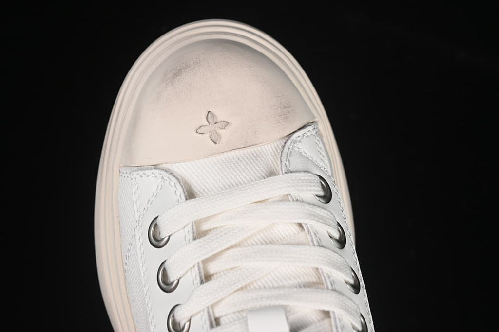 Top view of the toe with laces and a small four-petal motif.