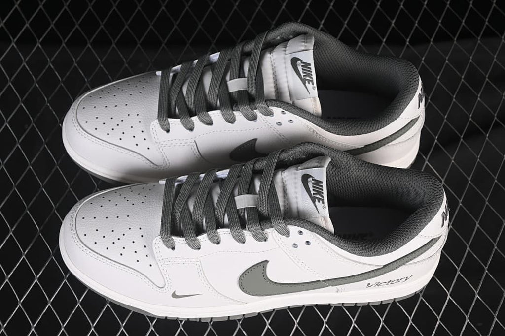 Pair of white and grey Nike SB Dunk Low sneakers shown from above.