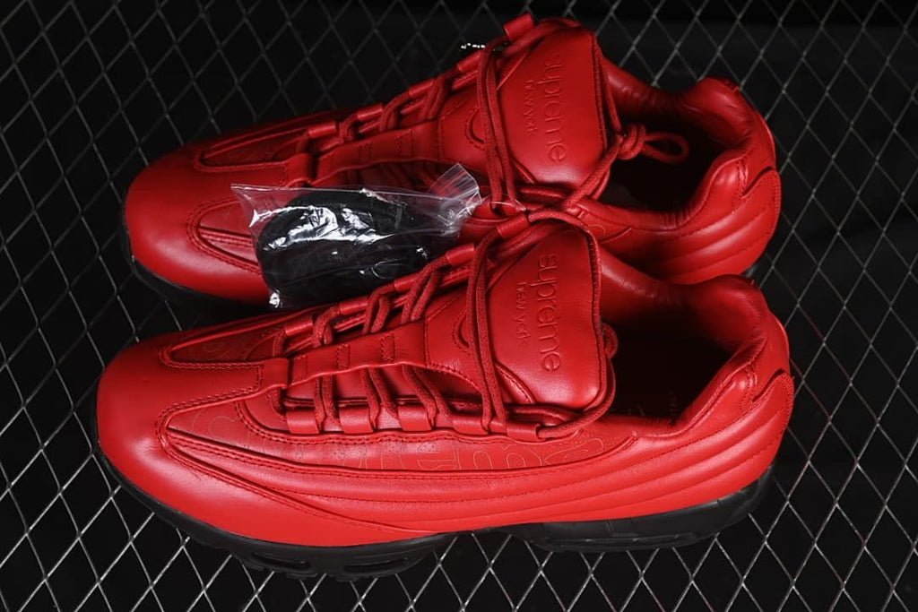 Pair of red and black sneakers shown from above with a small accessory