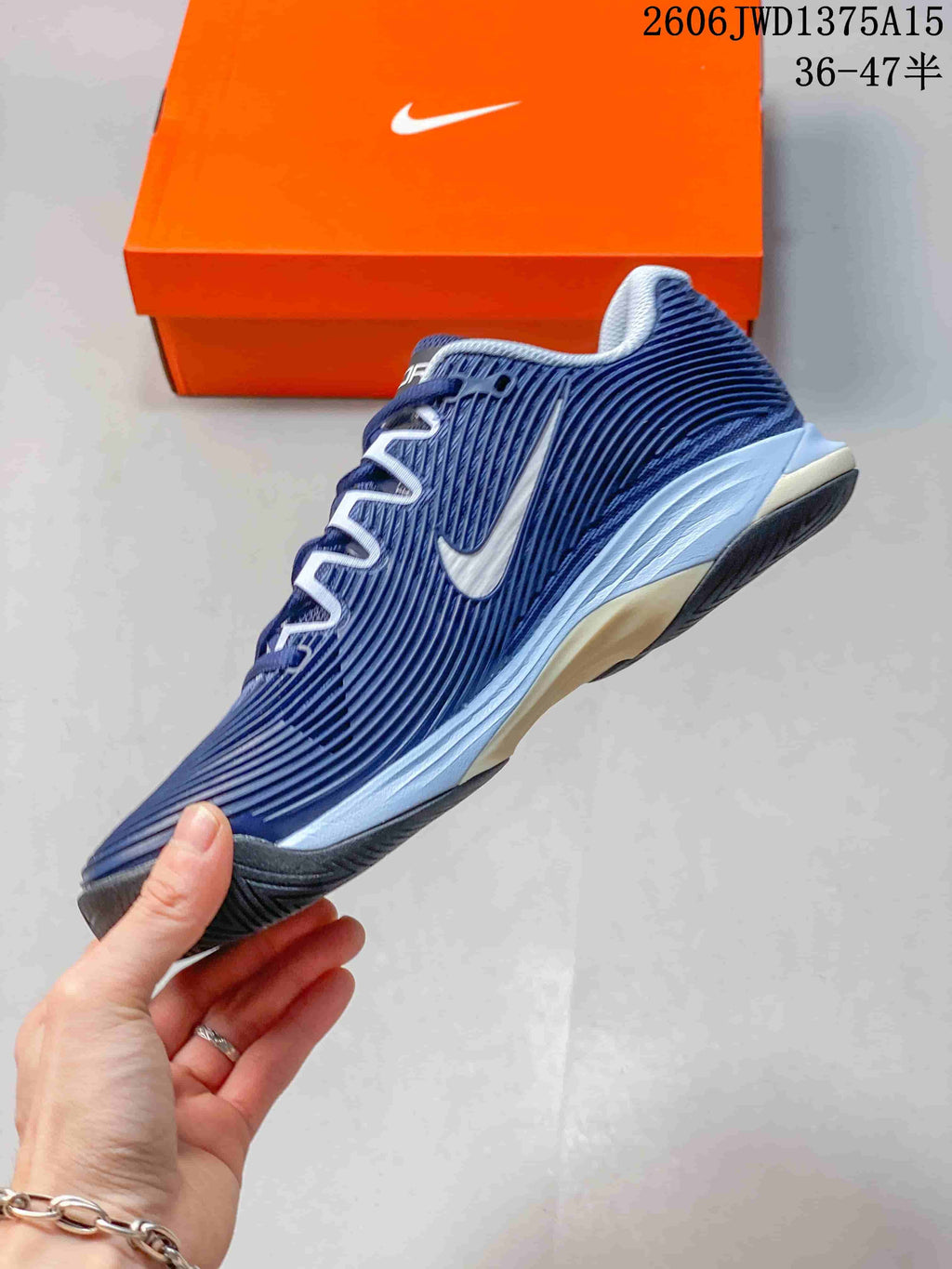 Side view of a blue and white Nike Vapor 12 tennis shoe