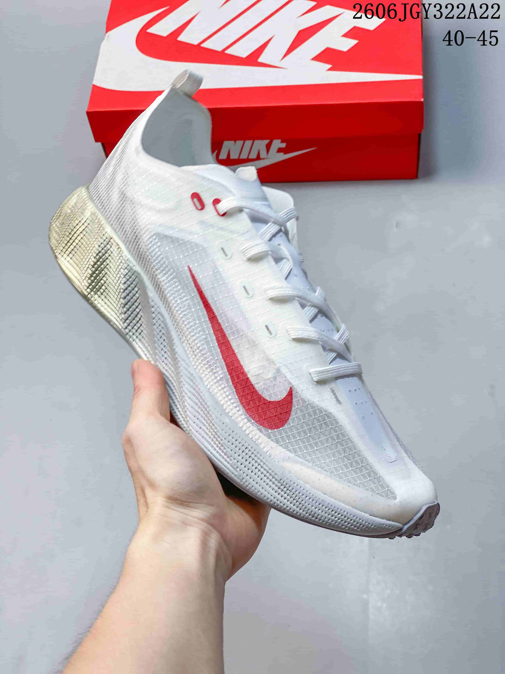 Angled side view of the white Nike Ava X sneaker with red accents.