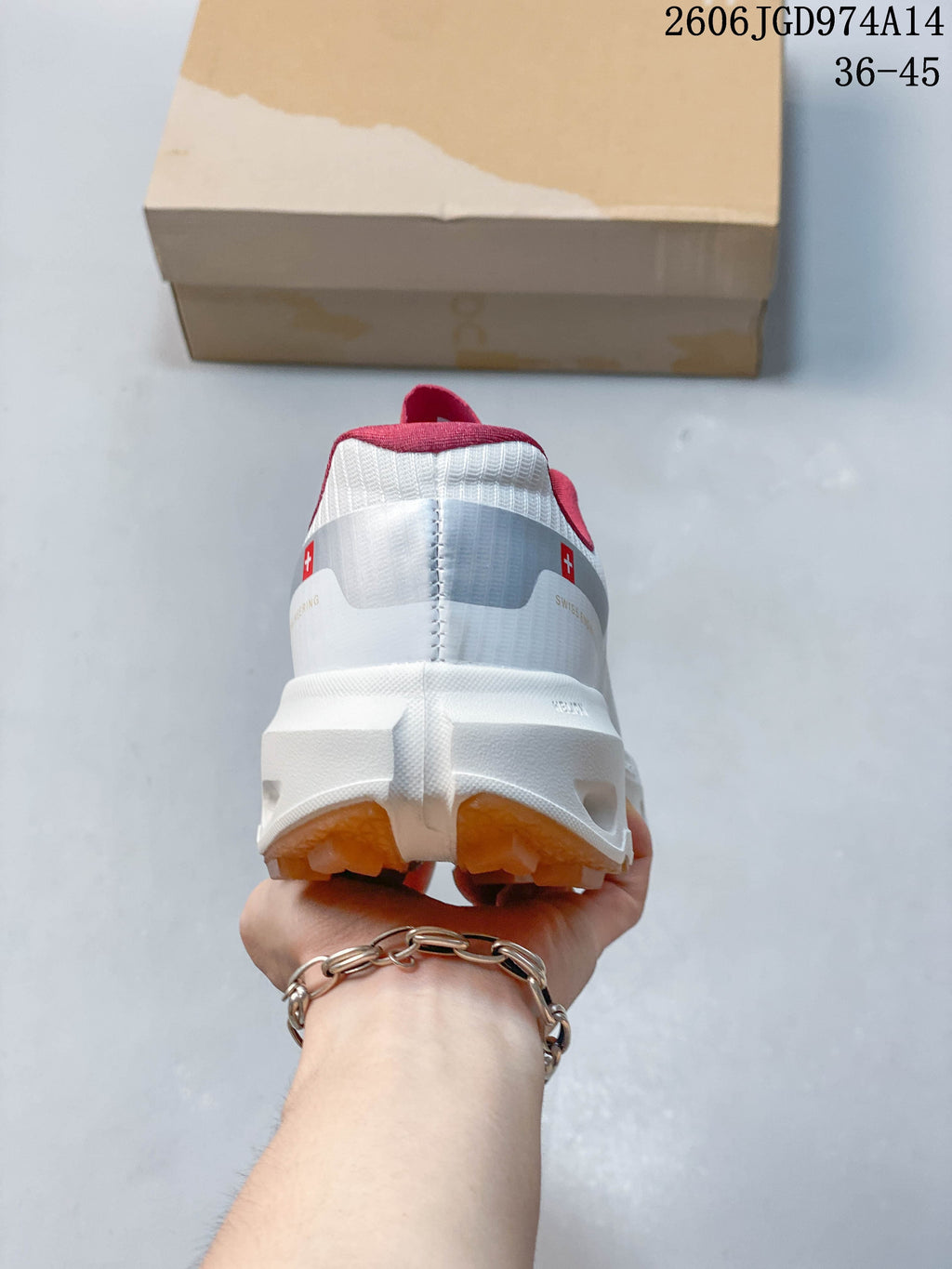 Rear view of a white trail running shoe with pink collar details and a gum-colored outsole.