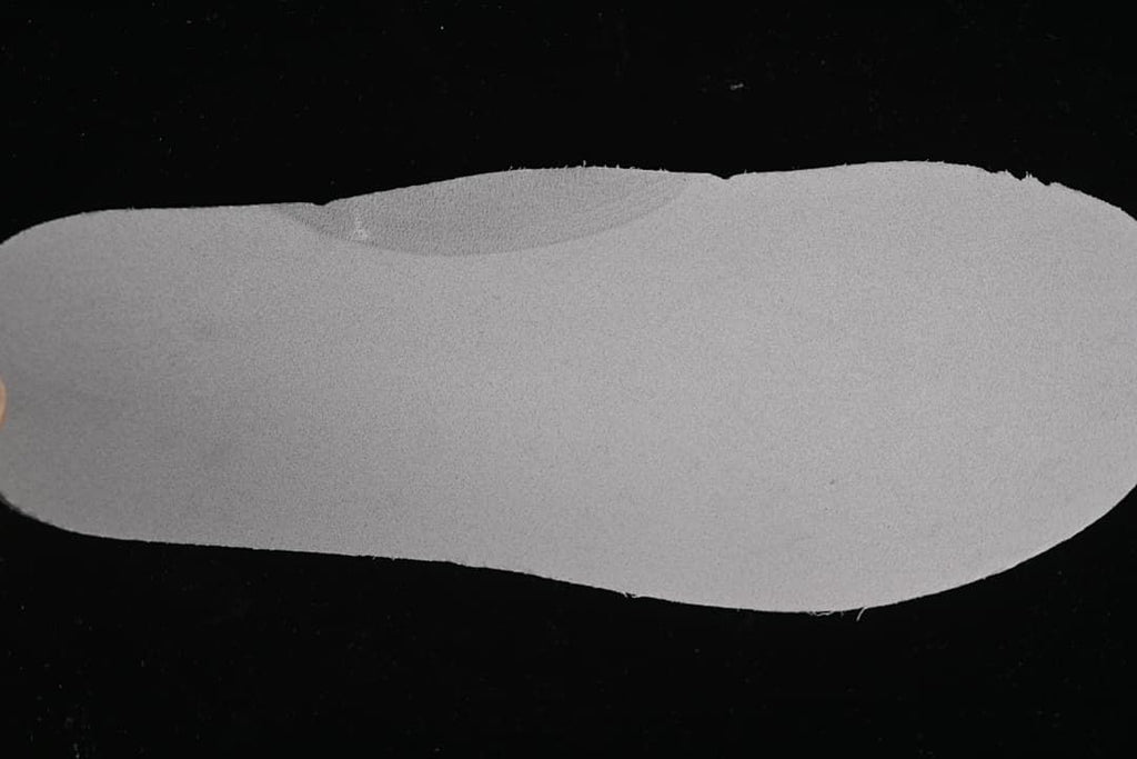 Light-colored shoe insole shown against a dark background