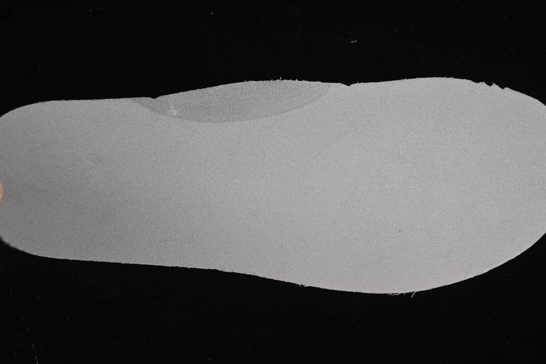 Light-colored shoe insole shown against a dark background
