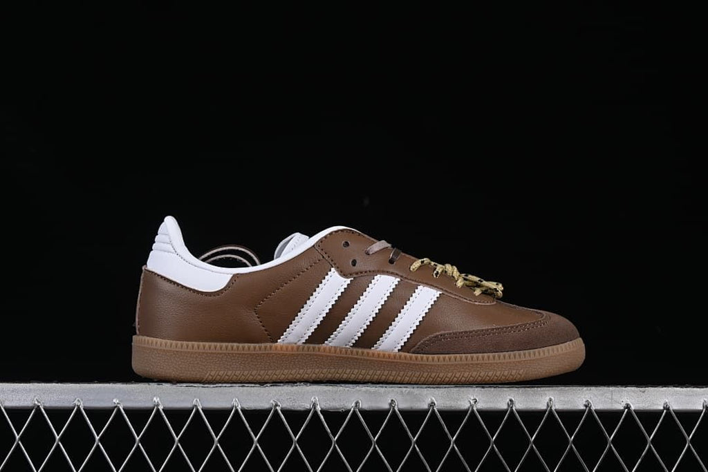 Side profile of a brown and white sneaker with three stripes and a gum-colored sole.