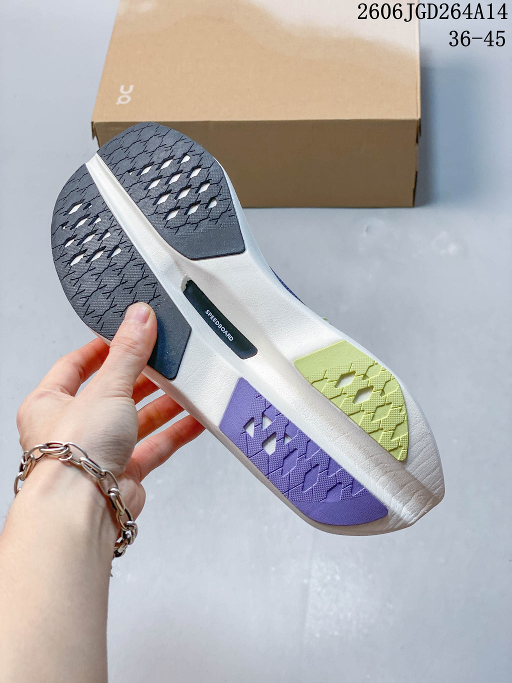 Underside of the running shoe showing a segmented outsole in dark, violet, lime, and light colors.