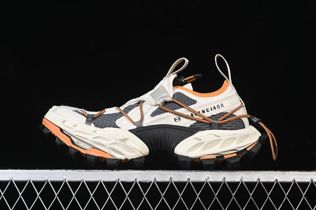 Side view of a white, charcoal, and orange Balenciaga Hike Trail sneaker