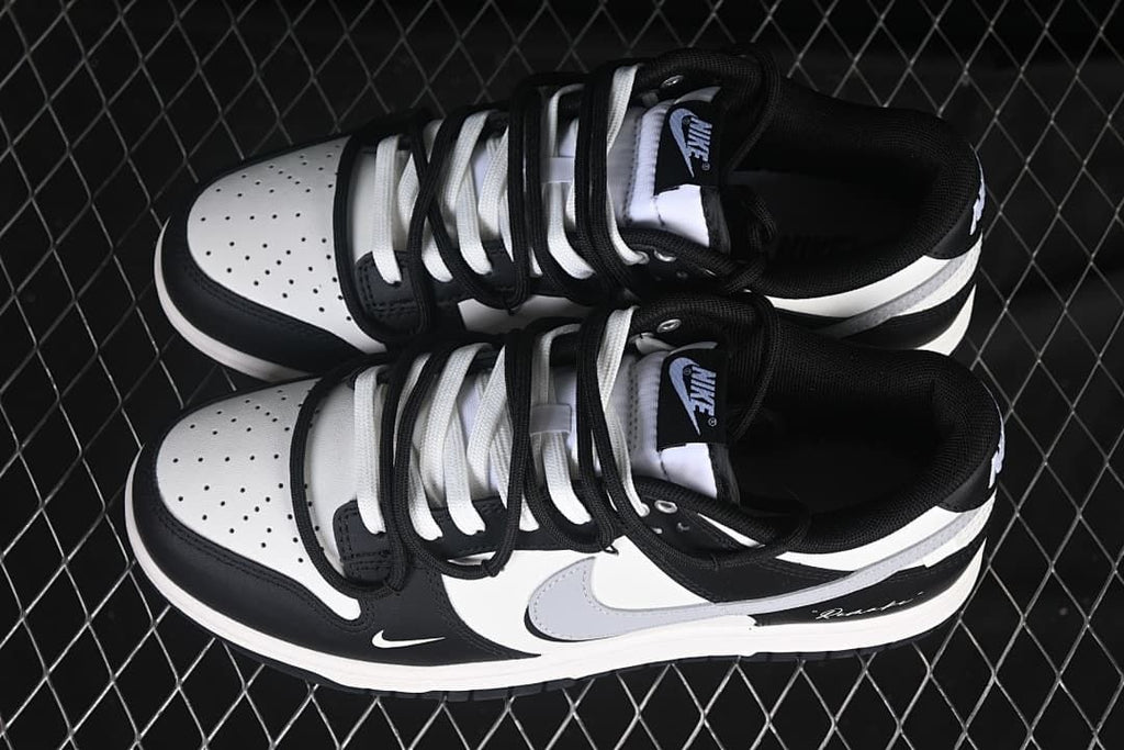 Top view of a pair of black-and-white Nike SB Dunk Low sneakers with contrasting laces and perforated toe boxes.