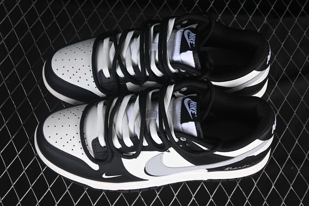 Top view of a pair of black-and-white Nike SB Dunk Low sneakers with contrasting laces and perforated toe boxes.