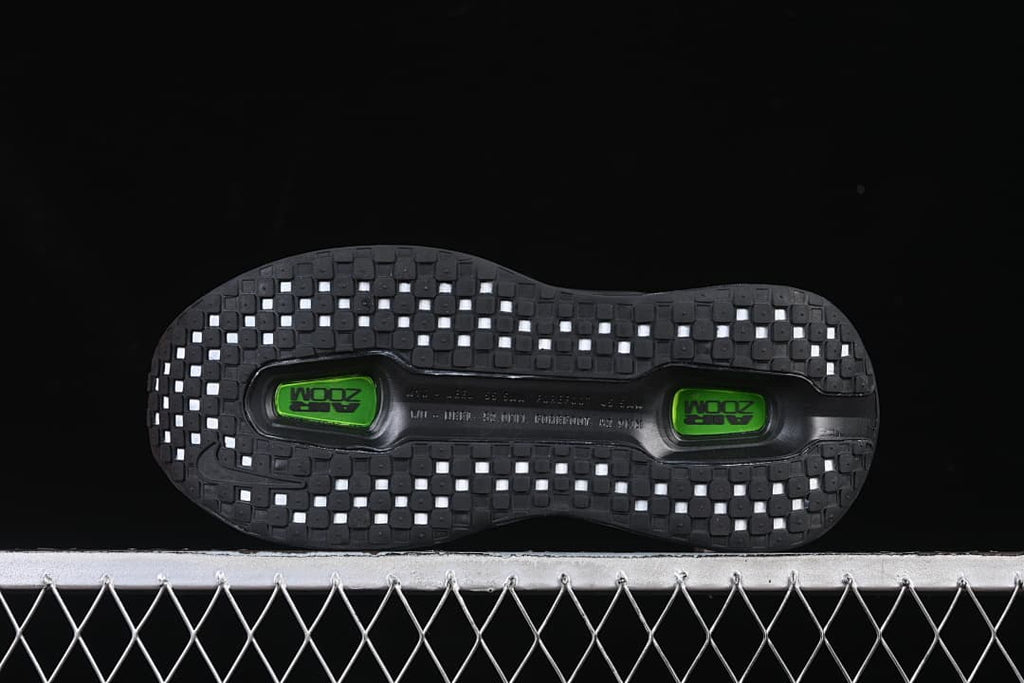 Bottom view of the outsole with square tread sections and two green inserts.