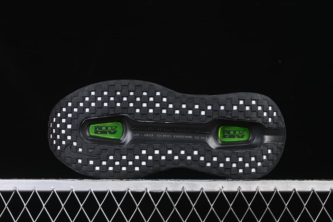Bottom view of the outsole with square tread sections and two green inserts.