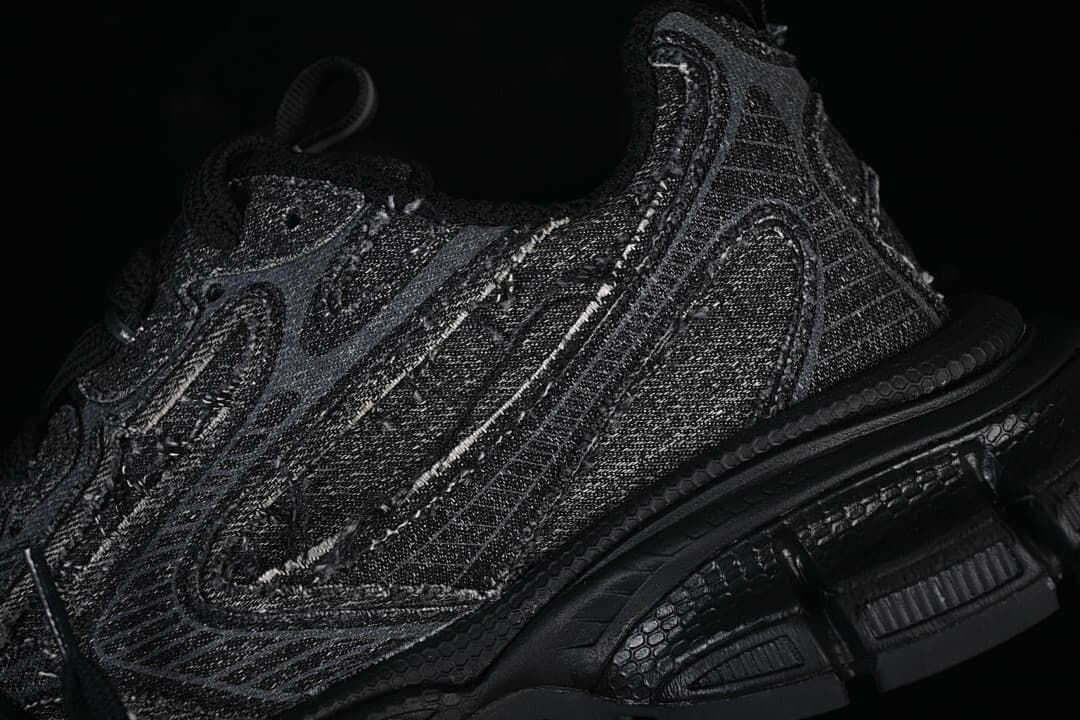 Close-up of layered side panels and segmented sole on the black sneaker.