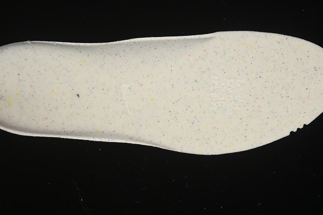 Close-up of a light-colored shoe insert with multicolored speckles.