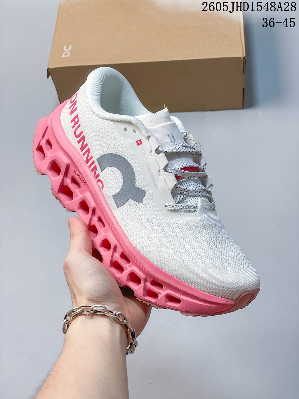 Angled side view of the white shoe with gray logo and bright pink sole