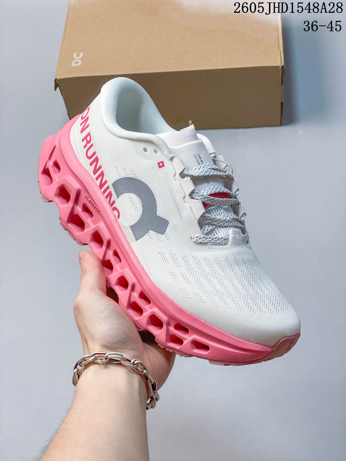 Angled side view of the white shoe with gray logo and bright pink sole