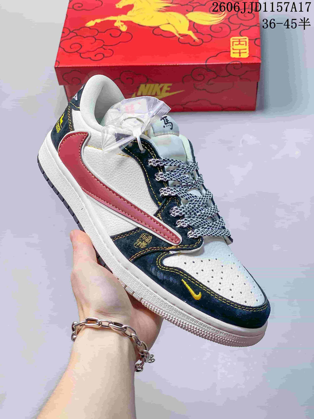 Close view of a white sneaker with dark navy and red overlays, yellow stitching, and patterned laces.