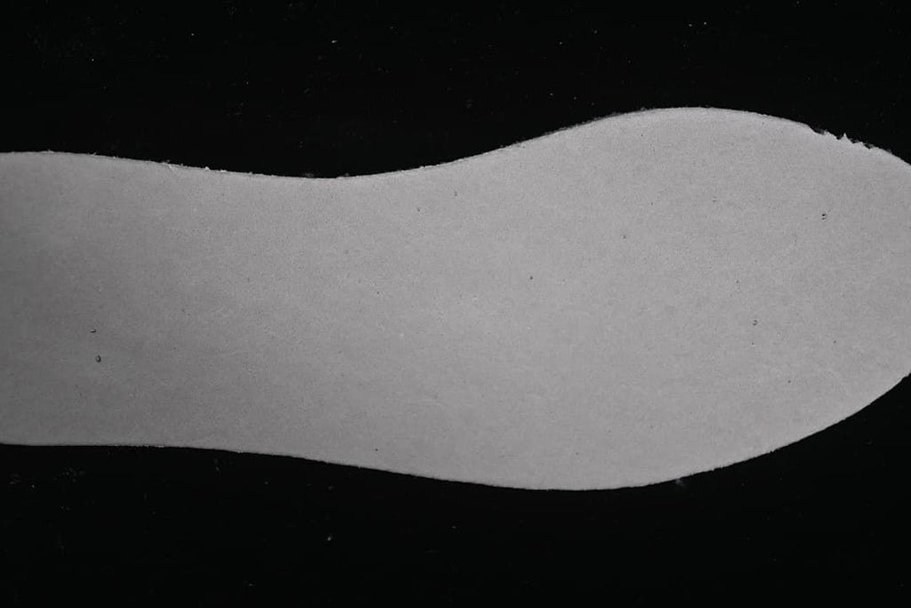 Light-colored shoe insole shown against a dark background