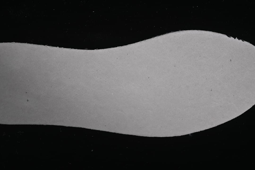 Light-colored shoe insole shown against a dark background