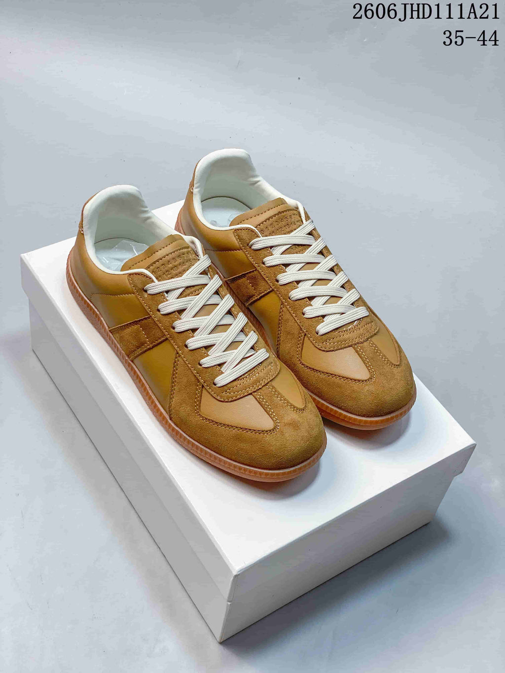 Pair of tan low-top Replica-style sneakers with cream laces and gum-colored soles