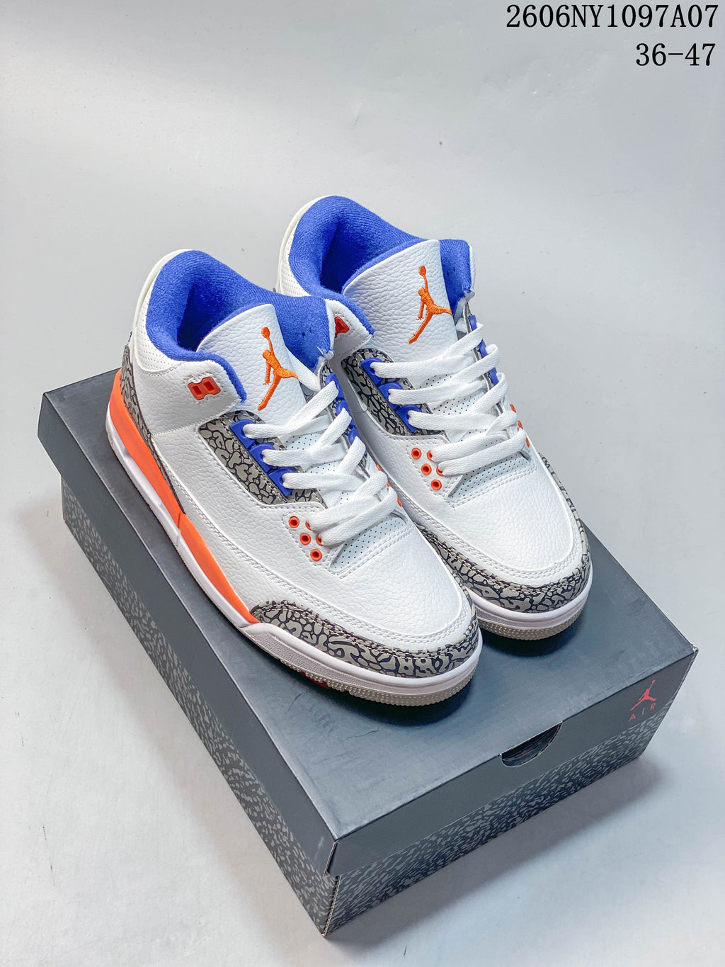 Pair of white Jordan Air Jordan 3 Knicks sneakers with blue and orange accents on a shoebox