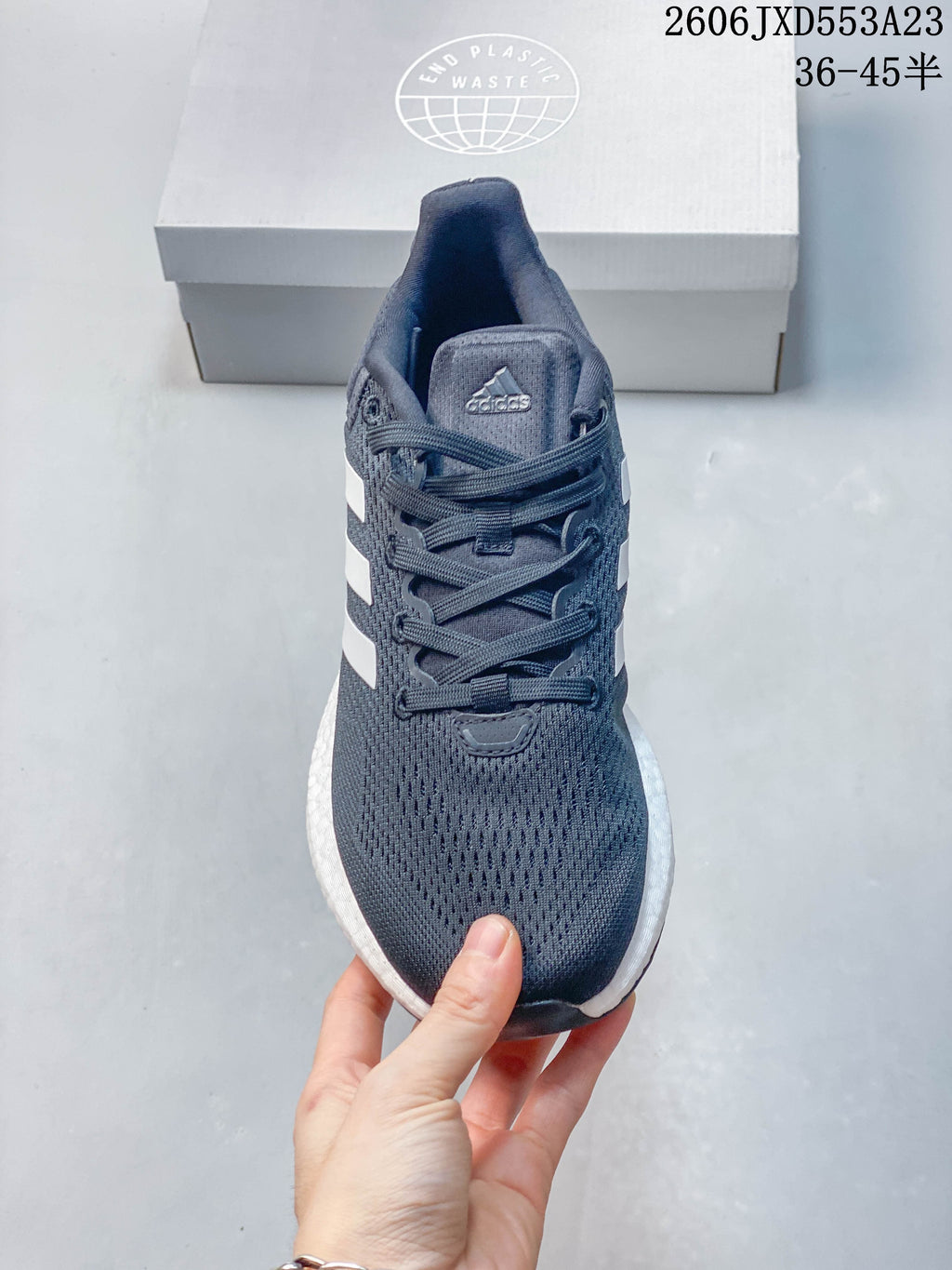 Front view of a navy Adidas PureBoost 21 shoe with laces and a knit-like upper.