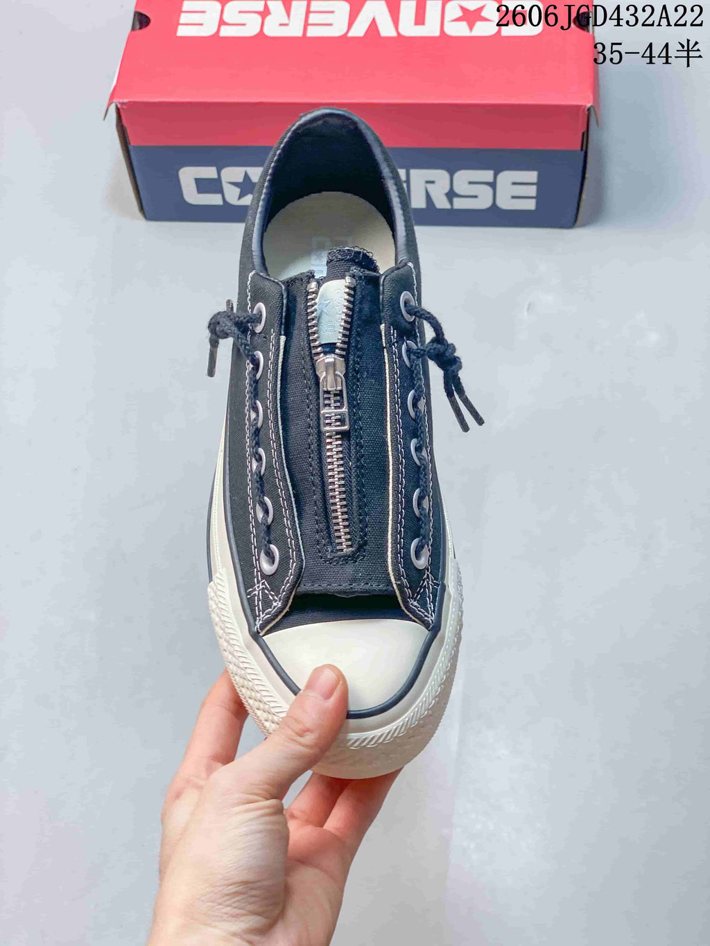 Top view highlighting the central zipper and side lacing on a black Converse sneaker.