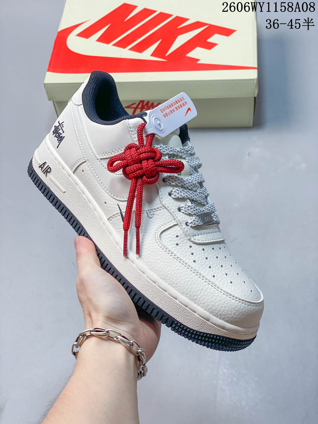 Angled view of the sneaker's lateral side, pale upper, navy outsole, and red lace detail.