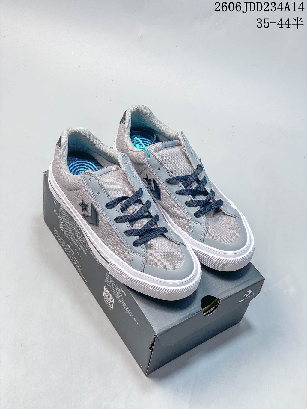 Gray and navy Converse low-top sneakers displayed on a shoe box