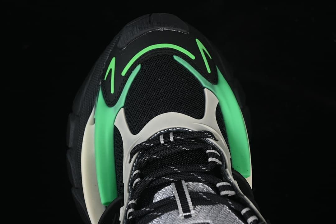 Top view of the sneaker toe and lace area with green and light-colored overlays
