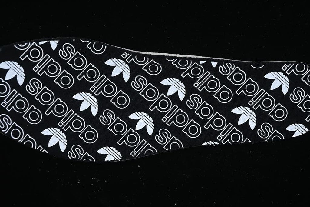 Black insole with repeating white adidas and trefoil graphics