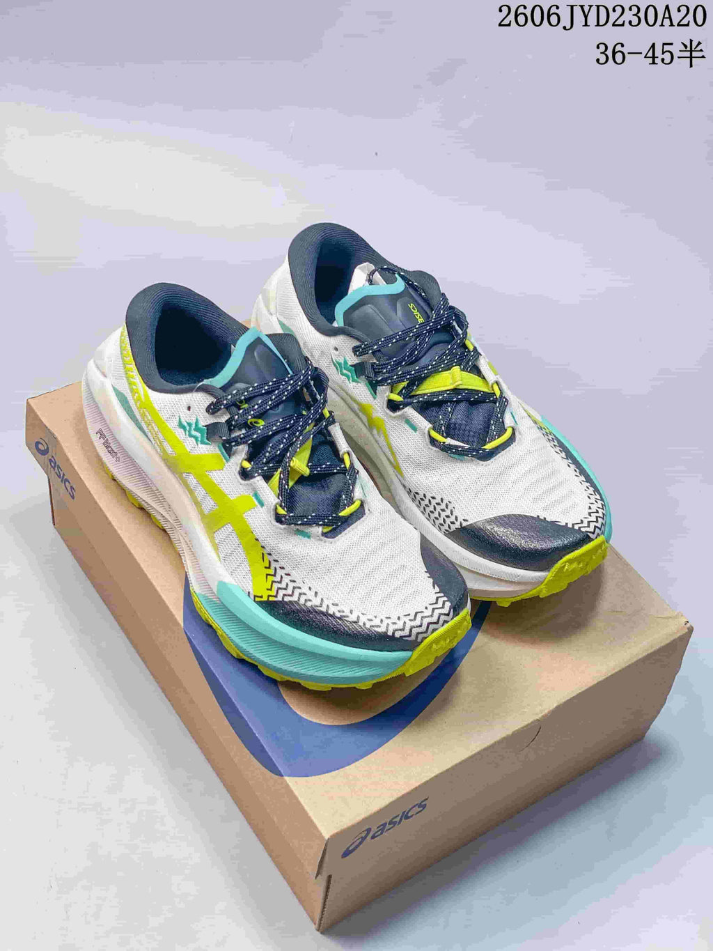 Two pairs of ASICS GEL-TRABUCO MAX 5 shoes in white with aqua and lime accents, and white with gray and orange accents