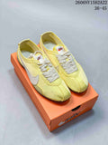 Pair of pale yellow Nike Moon Shoe OG low-top sneakers with cream laces and white Swoosh details on an orange box