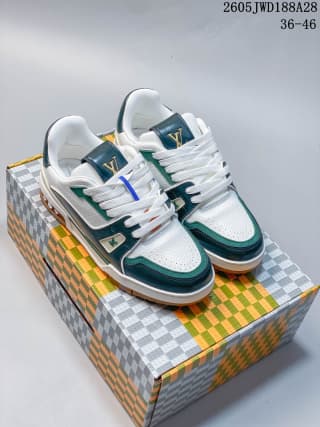 Pair of white and green low-top sneakers displayed on a patterned box