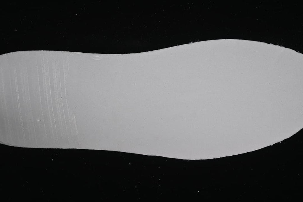 Plain white shoe outsole shown against a dark background