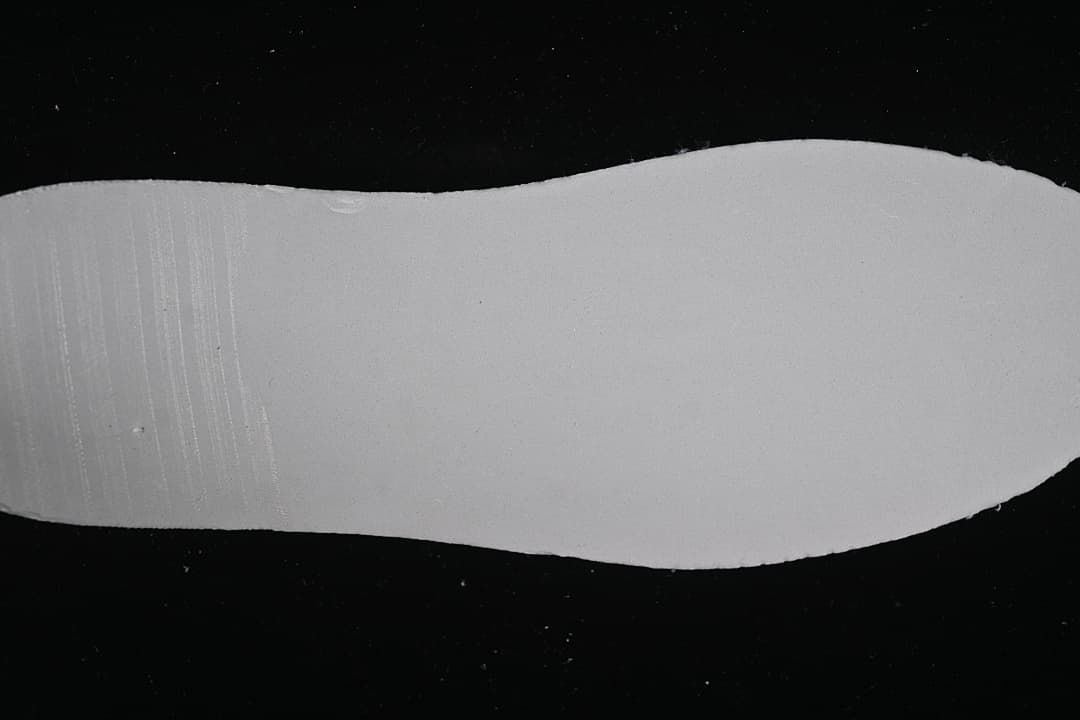 Plain white shoe outsole shown against a dark background
