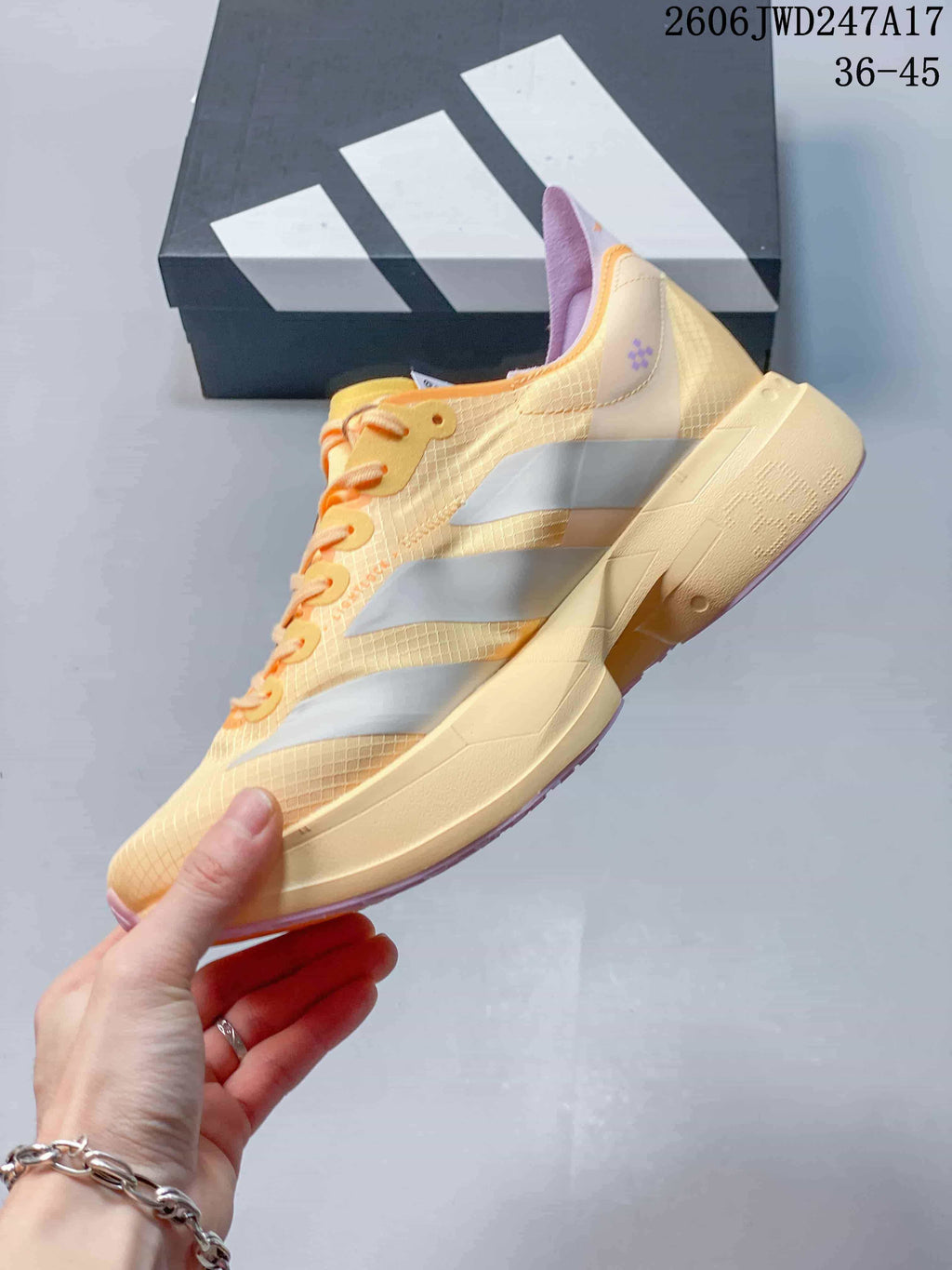 Side view of the pale yellow running shoe with silver stripes and lavender details.