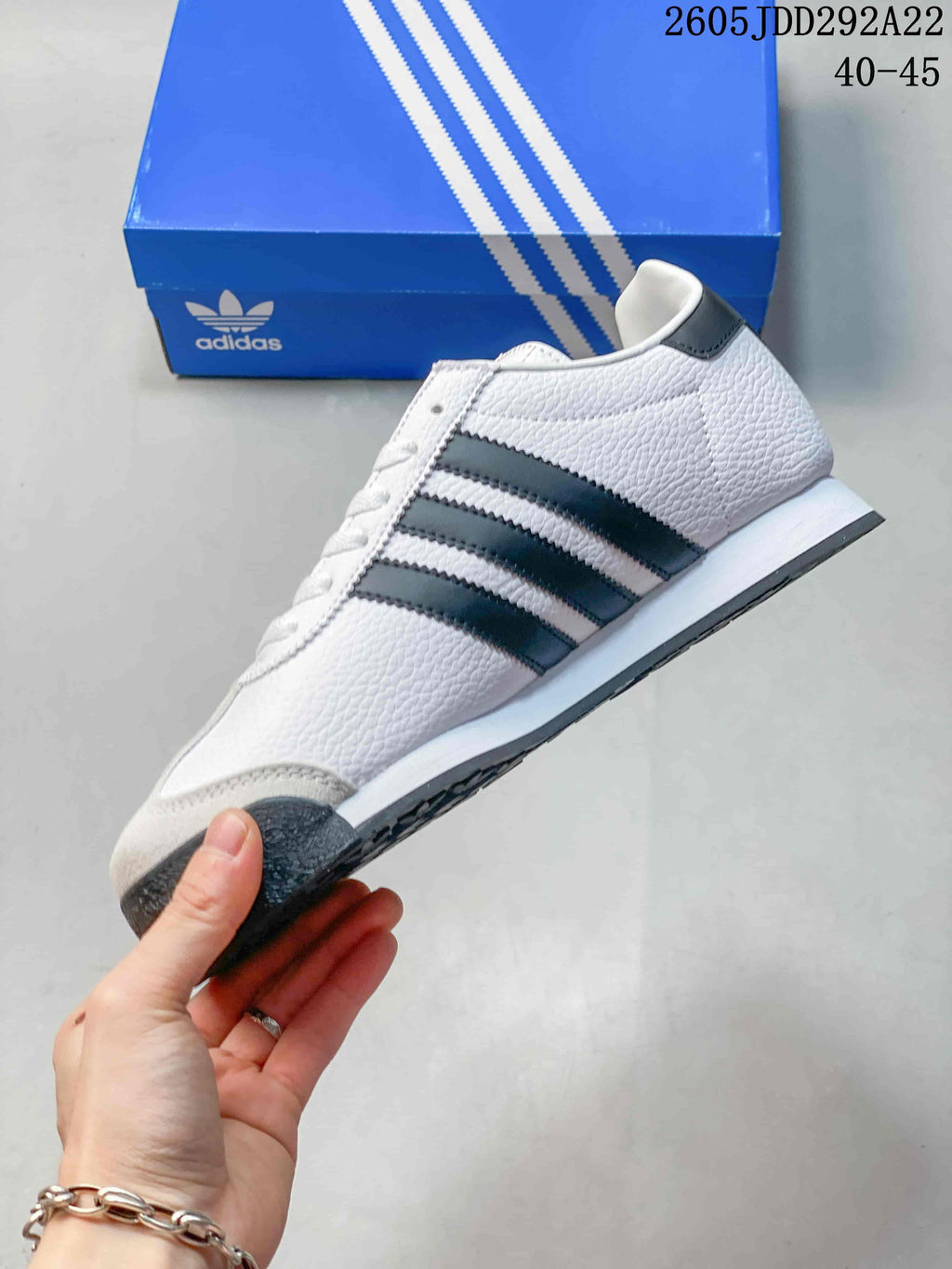 Side profile of a white Adidas Samoa sneaker with three dark stripes