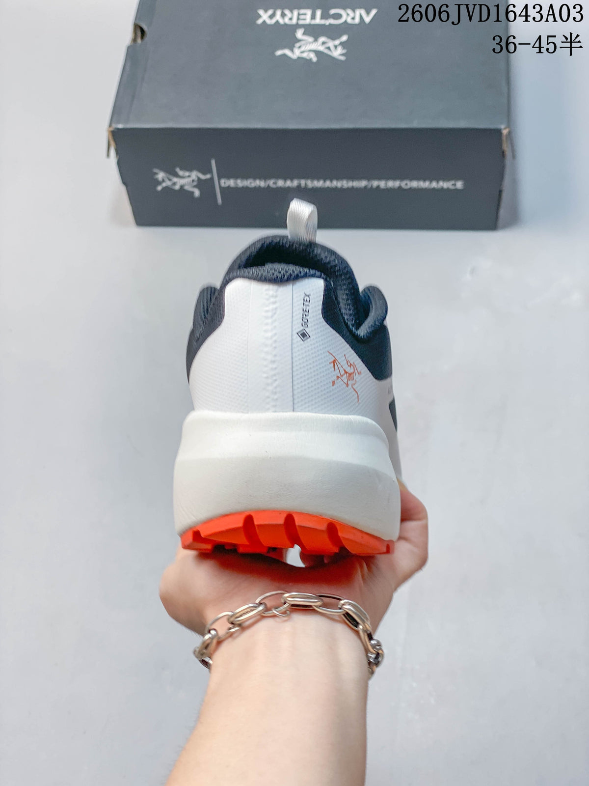 Rear view showing the white heel, navy collar, and orange outsole.