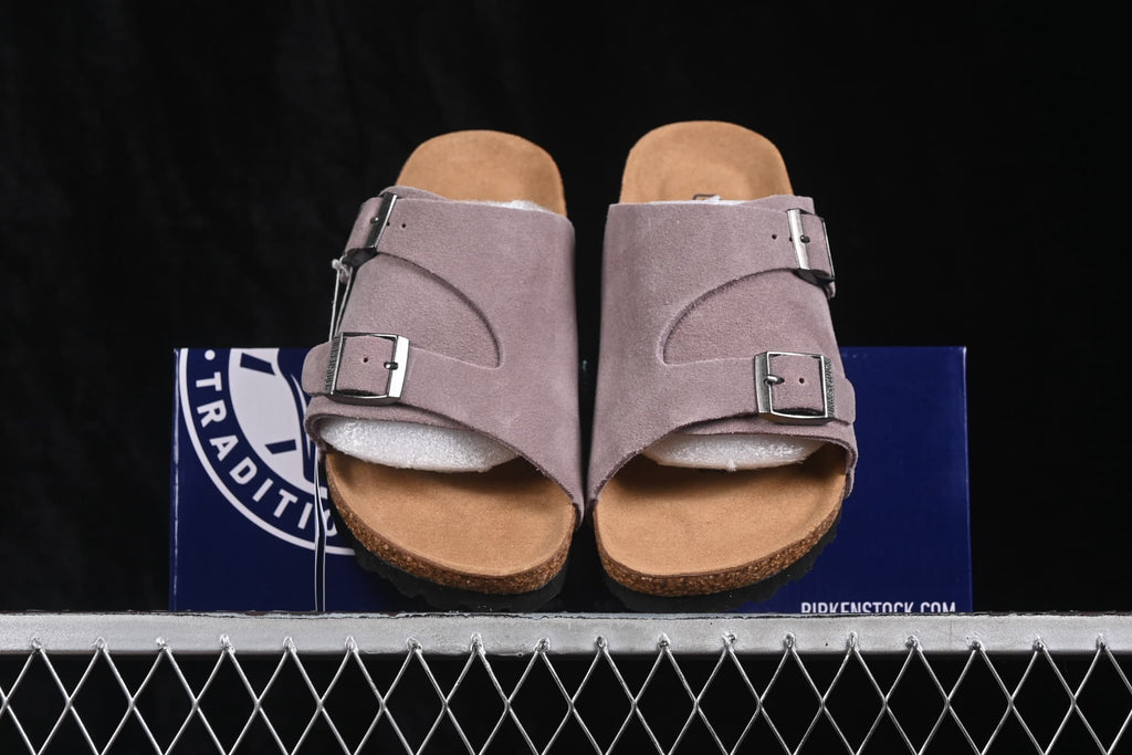 Front view of the lavender two-strap sandals displayed over a product box.