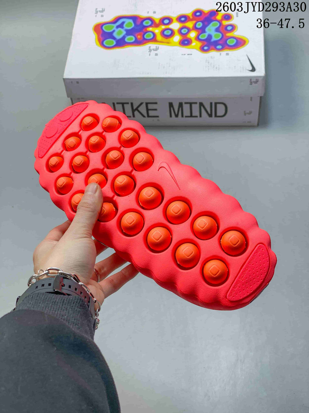 Underside of a bright red Nike Mind slide showing raised circular sole details.