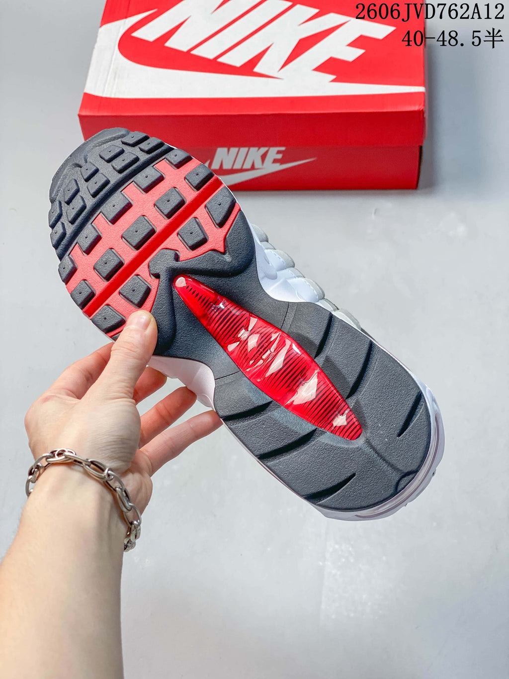Underside of a Nike Air Max 95 OG sneaker showing a dark outsole with red detailing.